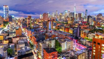 Vista nocturna de Nueva York con rascacielos iluminados. Refleja el aumento del precio de la vivienda en un 68% en la última década.