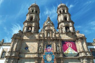 Fachada de la iglesia en Jalisco, ejemplo de arquitectura galardonada. Dos torres adornadas bajo cielo azul. Premio Jalisco de Arquitectura.