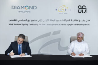 Ceremonia de inversión inmobiliaria turística en Yiti: dos hombres firman acuerdo. Logos de Diamond Developers, Yiti y Omran visibles.
