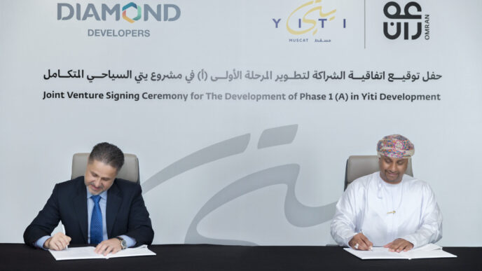 Ceremonia de inversión inmobiliaria turística en Yiti: dos hombres firman acuerdo. Logos de Diamond Developers, Yiti y Omran visibles.