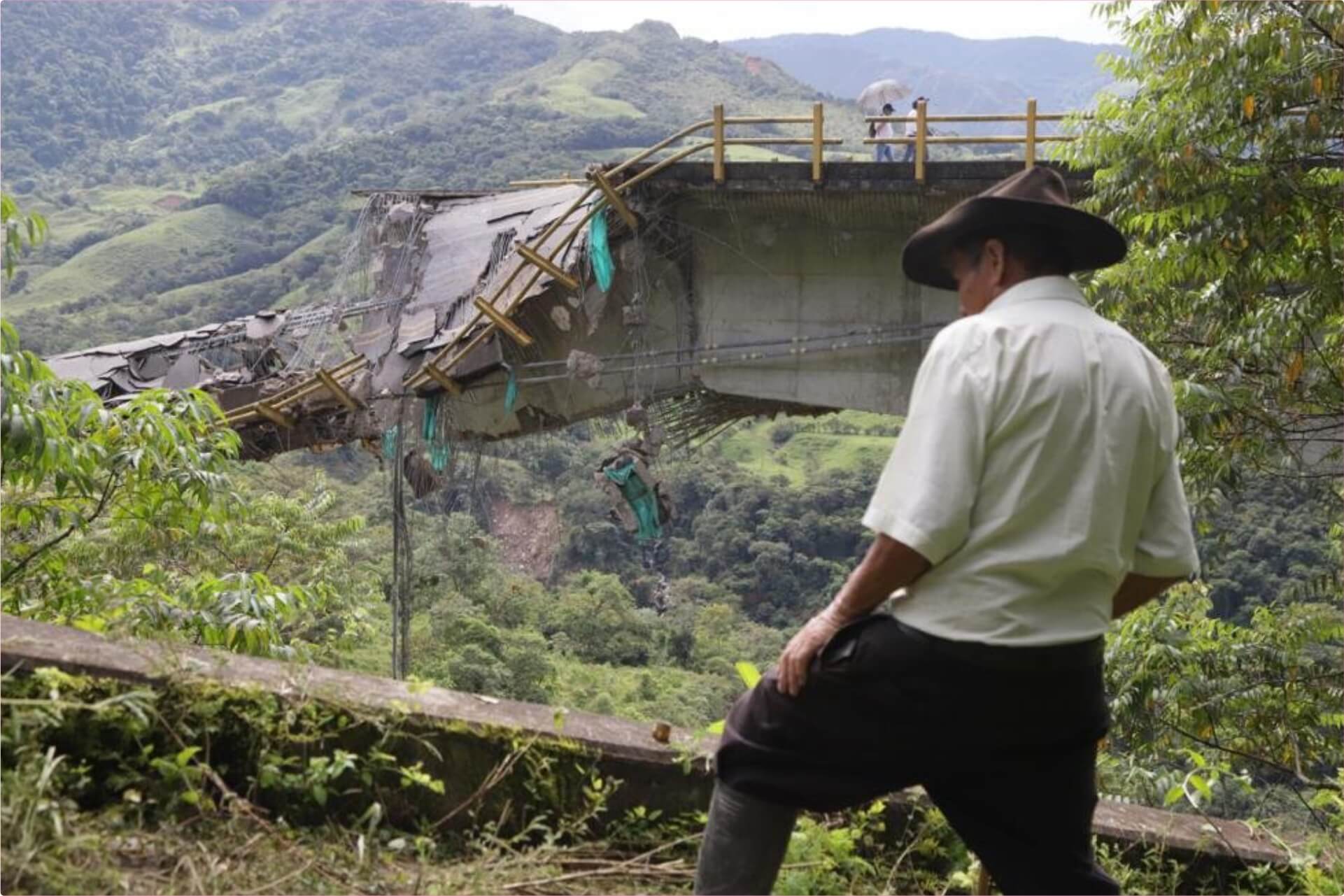 Puente colapsado en zona rural de LATAM. Un hombre observa los daños. Infraestructura afectada impacta el desarrollo urbano de la city.