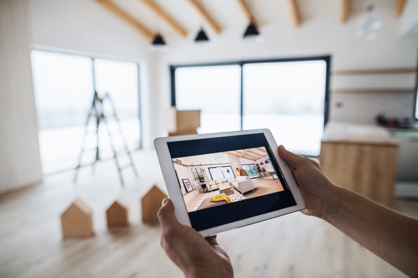Persona usando una tablet muestra diseño interior moderno, con casas de madera y escalera al fondo. Property Finder impulsa Proptech e inversión Stake.