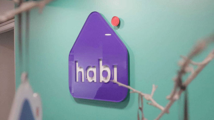 sponsors/branding
Logotipo de Habi, patrocinador de Inmobiliare Summits, en un evento de real estate. Diseño moderno en morado y blanco sobre pared turquesa.