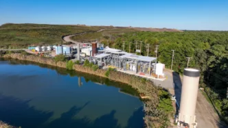 Vista aérea de la planta de RNG en New Jersey, mostrando la infraestructura moderna junto a un estanque y un paisaje natural. Impulso de energía renovable.