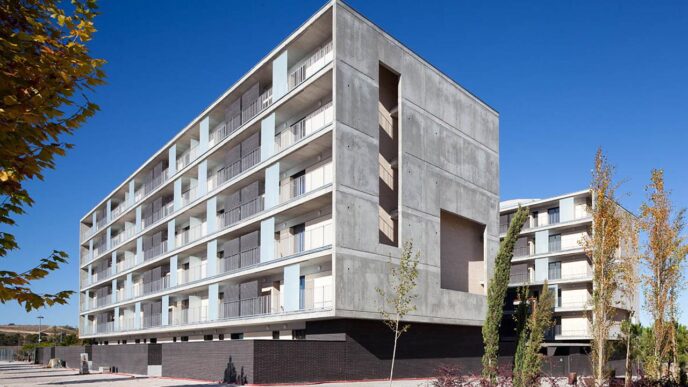 Edificio moderno de viviendas Ecobarrio en Argentina, con balcones y diseño arquitectónico minimalista bajo un cielo azul despejado. Vivienda accesible.