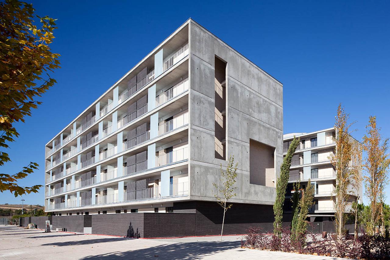 Edificio moderno de viviendas Ecobarrio en Argentina, con balcones y diseño arquitectónico minimalista bajo un cielo azul despejado. Vivienda accesible.
