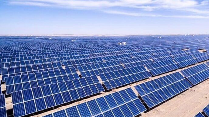 Vista aérea de un extenso proyecto solar de 300 MW en Rajasthan, con paneles azules alineados bajo un cielo azul claro. Energía renovable en acción.