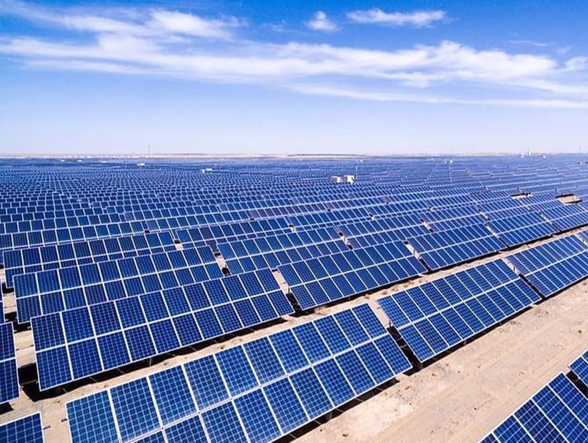 Vista aérea de un extenso proyecto solar de 300 MW en Rajasthan, con paneles azules alineados bajo un cielo azul claro. Energía renovable en acción.
