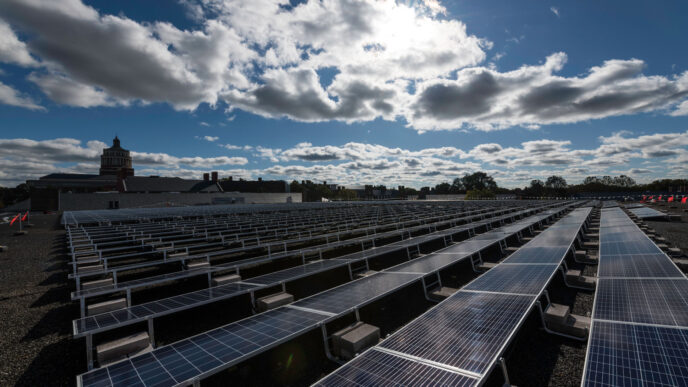 Imagen de paneles solares en Rochester, impulsando la sostenibilidad energética. Arquitectura histórica y cielo azul con nubes. Proyecto de energía solar.