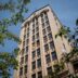 Edificio de oficinas antiguo en CDMX con posible reconversión, visto desde abajo a través de las ramas de los árboles, cielo azul. Beneficios fiscales.