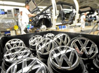 sponsors/branding
Logotipos de Volkswagen en primer plano, con trabajadores ensamblando coches en la fábrica. Imagen de marca y producción industrial.