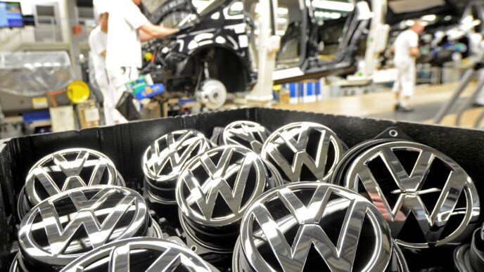 sponsors/branding
Logotipos de Volkswagen en primer plano, con trabajadores ensamblando coches en la fábrica. Imagen de marca y producción industrial.