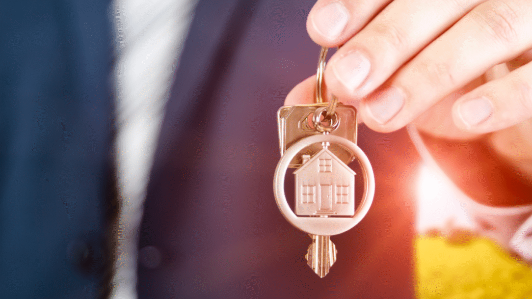 Inmobiliaria: Mano sostiene llaves con llavero de casa. Oportunidad de inversión en bienes raíces. Encuentra tu hogar en Tijuana.