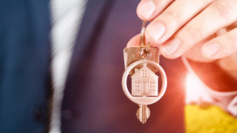 Inmobiliaria: Mano sostiene llaves con llavero de casa. Oportunidad de inversión en bienes raíces. Encuentra tu hogar en Tijuana.