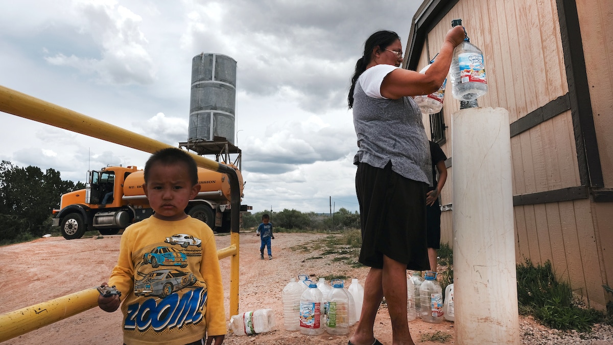 Crisis hídrica en LATAM: Mujer llenando botellas de agua potable con niño mirando. Escasez de agua en la ciudad, problema de real estate.