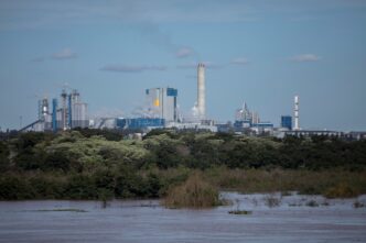 Vista del Molino Giot, Uruguay, un complejo industrial con chimeneas y edificios junto al río, reflejando el proyecto inmobiliario de recuperación.