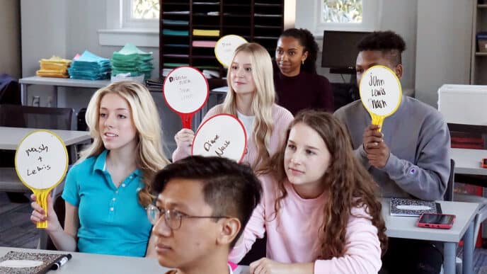 The category is none of the options.

Alt text: Estudiantes participan en clase, mostrando nombres en paletas. Aprendizaje activo en conferencia.