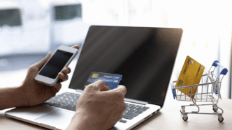 Persona comprando en línea con tarjeta de crédito y smartphone. Comercio electrónico, pagos digitales, compras seguras.