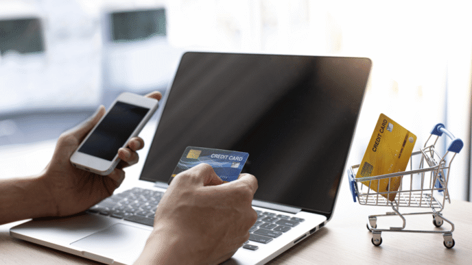 Persona comprando en línea con tarjeta de crédito y smartphone. Comercio electrónico, pagos digitales, compras seguras.