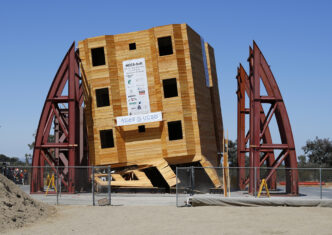 Edificio de madera inclinado tras simulación de riesgo sísmico, factor determinante en la construcción. NEES@UCSD prueba resistencia estructural.