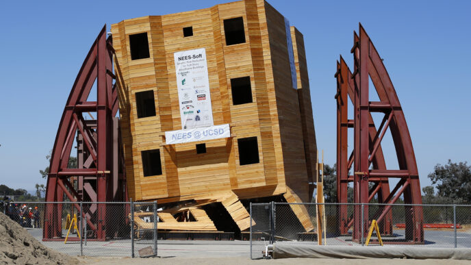 Edificio de madera inclinado tras simulación de riesgo sísmico, factor determinante en la construcción. NEES@UCSD prueba resistencia estructural.