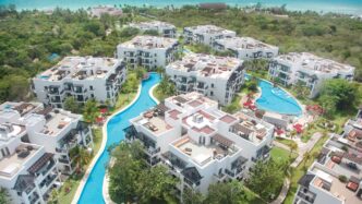 Vista aérea del nuevo hotel The Fives en Riviera Maya. Muestra la arquitectura moderna, piscinas serenas y exuberante vegetación tropical. Resorts lujosos.