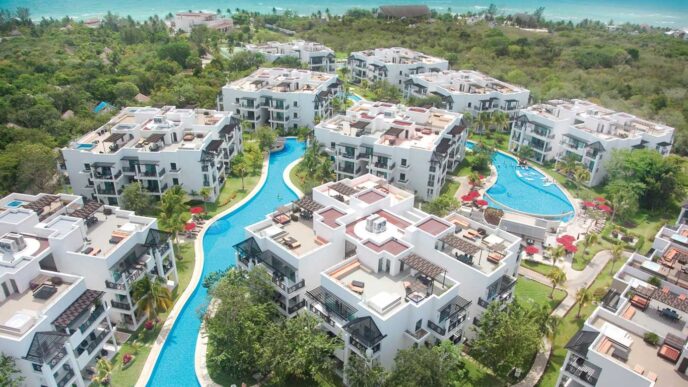 Vista aérea del nuevo hotel The Fives en Riviera Maya. Muestra la arquitectura moderna, piscinas serenas y exuberante vegetación tropical. Resorts lujosos.