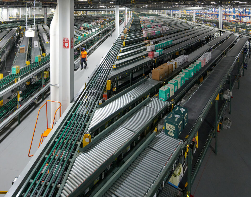 Visión amplia de un almacén con cintas transportadoras y operario. Automatización y tecnología transformando el real estate industrial.