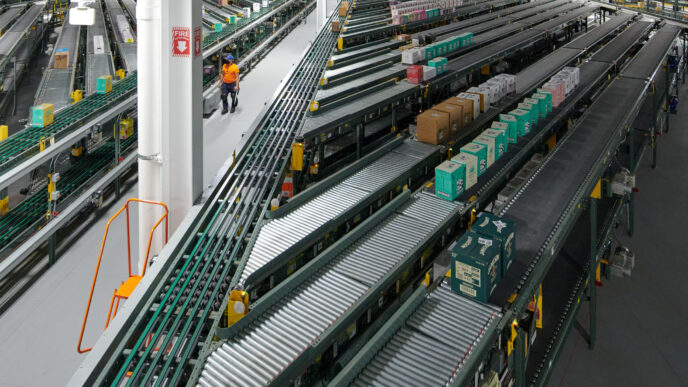 Visión amplia de un almacén con cintas transportadoras y operario. Automatización y tecnología transformando el real estate industrial.