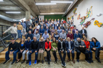 Grupo diverso en escalera, celebrando expansión de Sagard en Manhattan, con implicaciones LATAM. Ambiente moderno y colaborativo. Inversión y negocios.