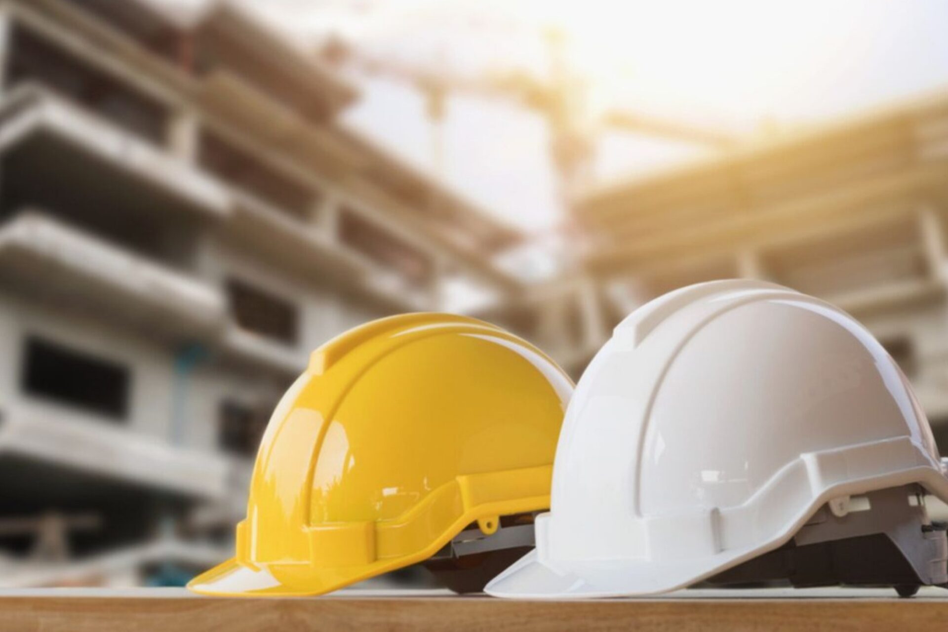 Venue/architecture.
Cascos de construcción amarillo y blanco frente a edificio en obra. Sector inmobiliario en México y LATAM. Seguridad en proyectos de real estate.