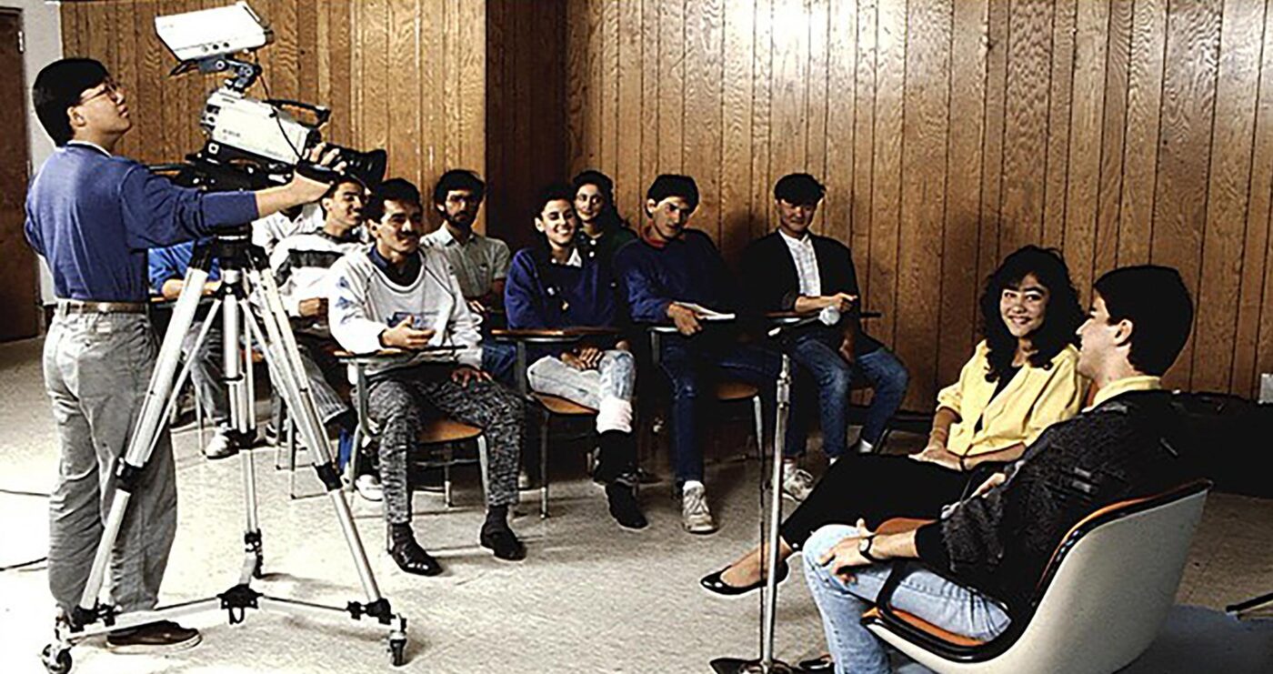 Escena de filmación con camarógrafo grabando a personas sentadas, posiblemente para el Plan Estatal de Desarrollo 2022-2027 de Nuevo León.