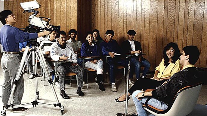 Escena de filmación con camarógrafo grabando a personas sentadas, posiblemente para el Plan Estatal de Desarrollo 2022-2027 de Nuevo León.