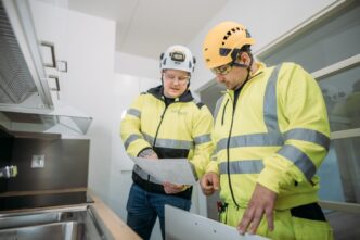 Dos ingenieros de la construcción revisan planos en una cocina moderna. Sector de la construcción se revoluciona con LCI México, innovación.
