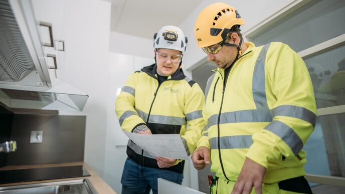 Dos ingenieros de la construcción revisan planos en una cocina moderna. Sector de la construcción se revoluciona con LCI México, innovación.