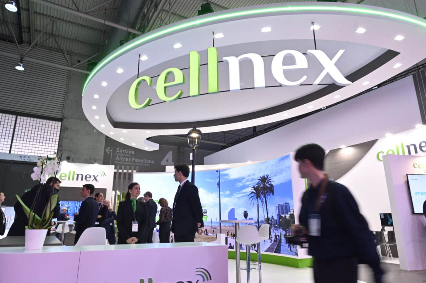 Stand de Cellnex en España, mostrando tecnología smart city en Montserrat. Personas visitan el espacio con diseño moderno y elementos tecnológicos.