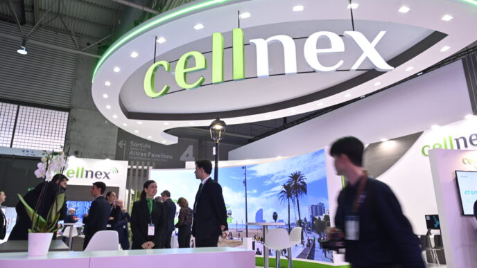 Stand de Cellnex en España, mostrando tecnología smart city en Montserrat. Personas visitan el espacio con diseño moderno y elementos tecnológicos.