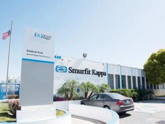 Fachada de la planta de Smurfit Kappa en Tamaulipas tras la inversión de 23.5 mdd para modernización. Edificio corporativo con bandera y letrero.