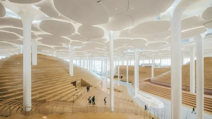 Interior de la biblioteca diseñada por Snøhetta, con espacio de lectura amplio, columnas blancas y diseño moderno. Inauguración de la biblioteca.