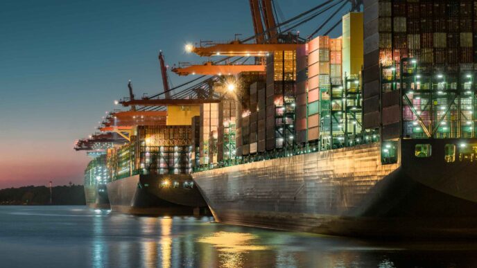 Vistas nocturnas de buques de carga en puerto mostrando logística marítima sostenible e impacto en el Real Estate, con grúas iluminadas.