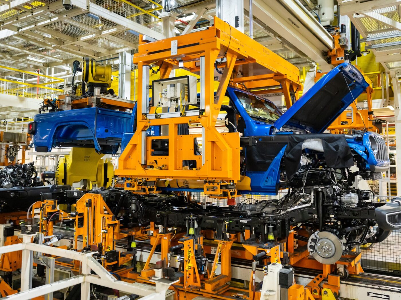 Línea de ensamblaje de Stellantis en EE.UU., con carrocerías azules en proceso. Inversión de 13,000 mdd para modernizar fábricas. Detalle industrial