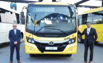 Presentación de autobús Tata Motors Euro 6 LP 716 amarillo. Dos hombres de pie frente al vehículo, mostrando la transición a vehículos comerciales Euro 6.