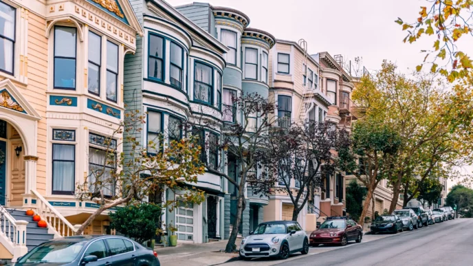 Calle con casas victorianas y coches aparcados. Inmobiliario residencial, arquitectura clásica, tendencia co-living. IA aplicada al mercado 2025.