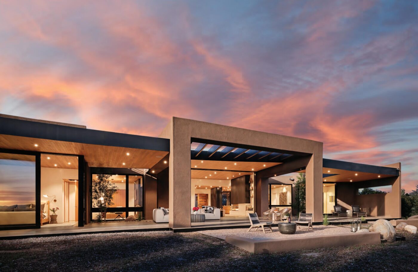 Diseño moderno de vivienda rehabilitada por The Home Depot en México, con amplios ventanales y terraza al atardecer. Construcción sustentable y actual.