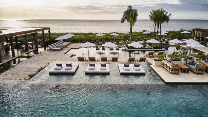 Vista aérea de The Riviera Maya EDITION at Kanai, un nuevo hotel de lujo en Yucatán. Muestra piscinas, tumbonas y vegetación frente al mar Caribe.