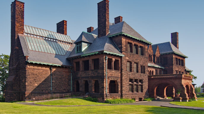 Fachada de vivienda nueva de piedra rojiza con múltiples chimeneas, césped verde y cielo azul. Crecimiento del 13.8% anual según Tinsa México.