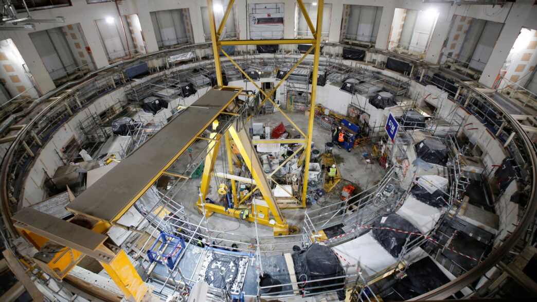 Vista aérea del Tokamak experimental en construcción, impulso energético sostenible en China, con andamios y maquinaria amarilla. Innovación y tecnología.