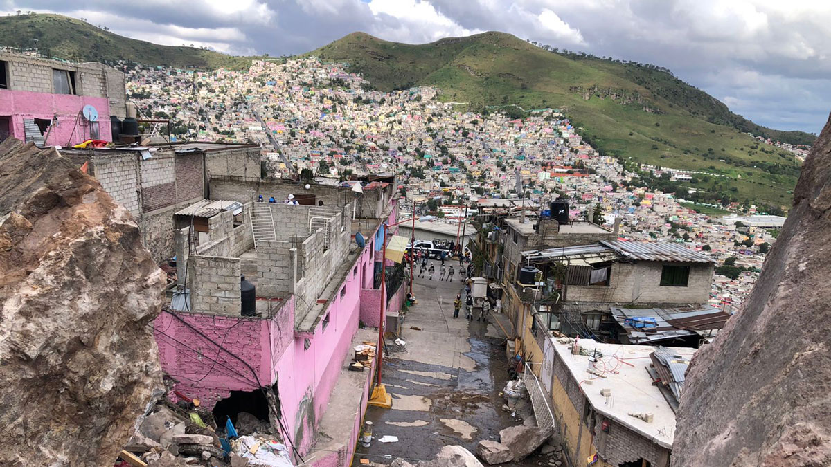 Vista panorámica de una ciudad en LATAM, con casas coloridas en una ladera. Arquitectura urbana y entorno natural contrastantes.