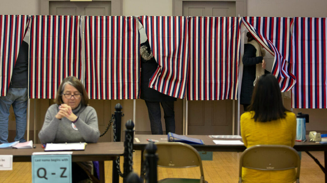 speakers/headshot
Personas votando en cabinas con cortinas de rayas rojas, blancas y azules. Elecciones en EE. UU. con votantes y mesas de registro.