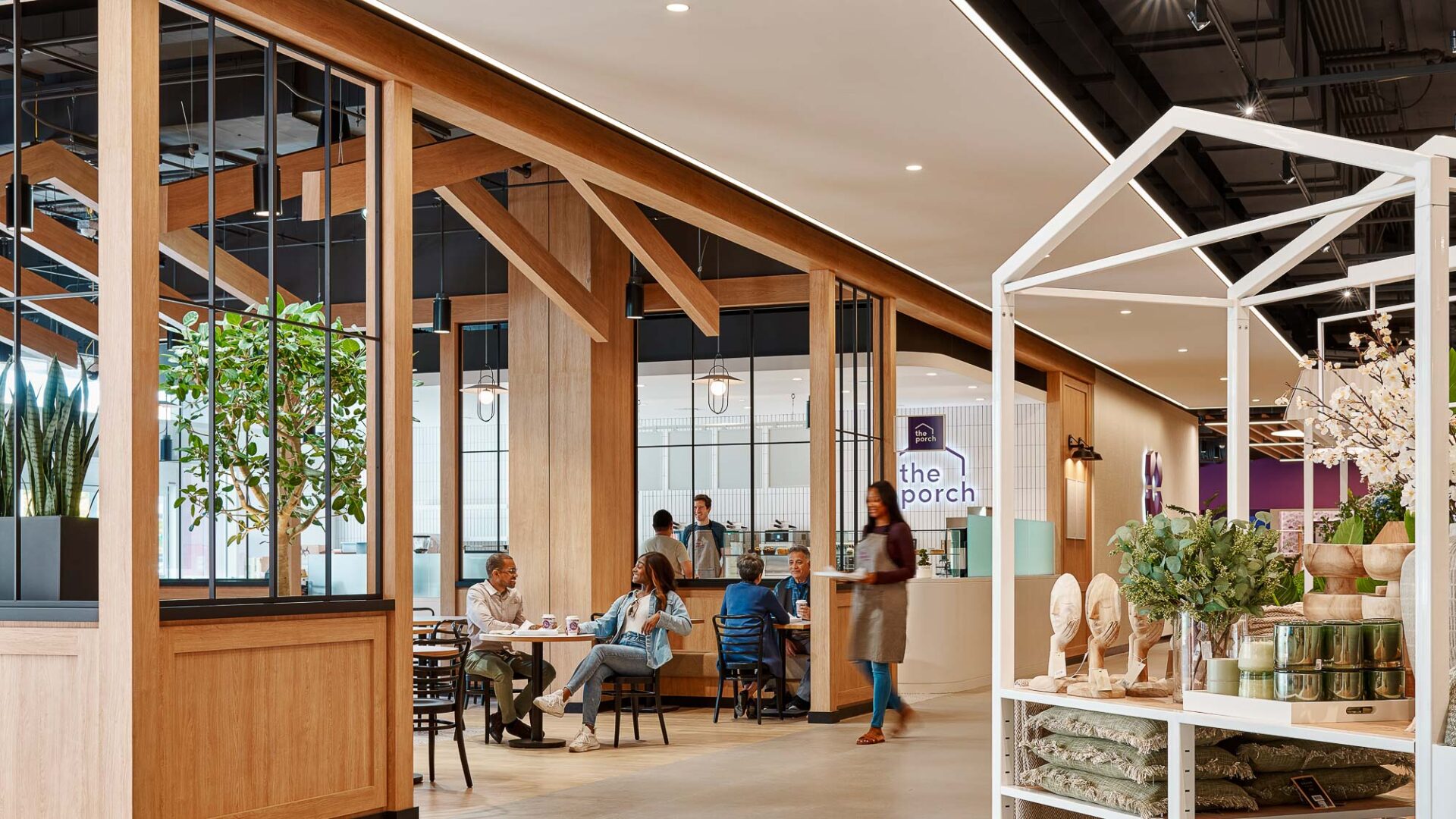 Espacio retail transformado en oficina en LATAM. Diseño interior con mesas, vegetación y área de descanso. Ambiente moderno y acogedor, ideal para trabajar.